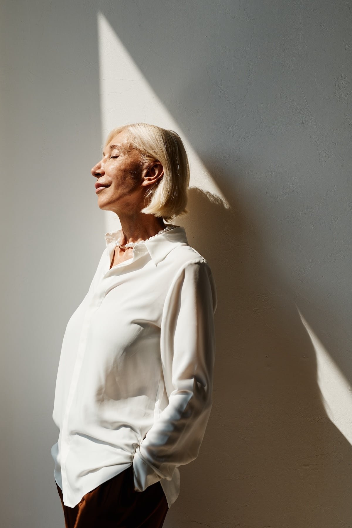beautiful elegant mature woman standing on shadowy wall beautiful elegant mature woman standing on shadowy wall