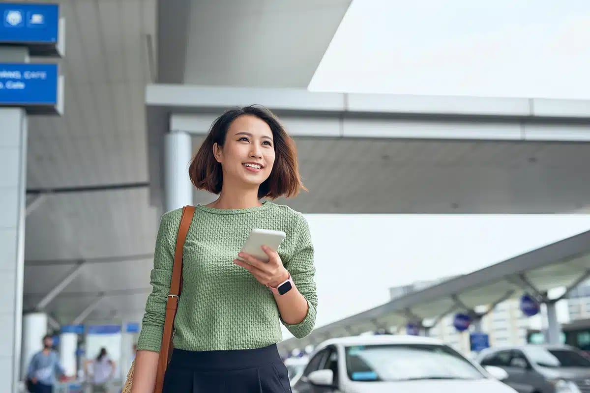 Asian woman is checking her smartphone as she waits in airport in Asia
