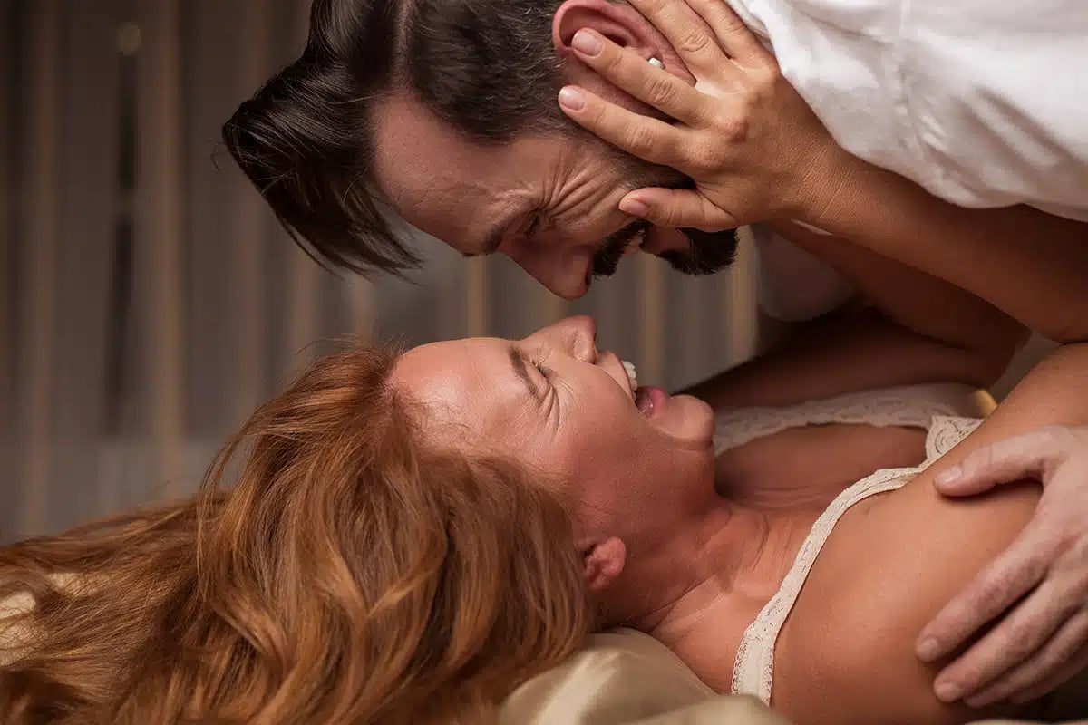 Side view of excited man is lying over woman in bed
